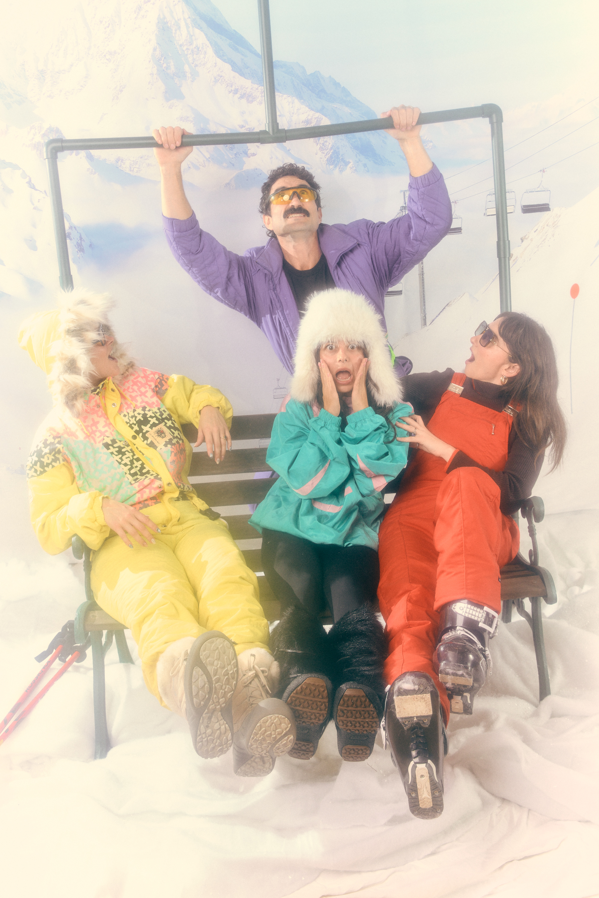 Limber crew in full 80s ski gear piled onto a chairlift bench prop